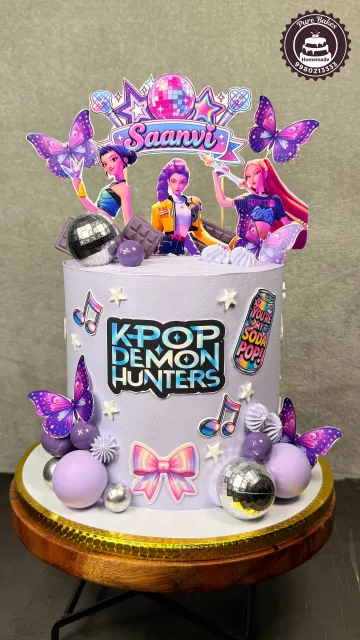 Purple Kpop Demon Hunters themed birthday cake with butterflies, disco balls, musical notes, and colorful character toppers