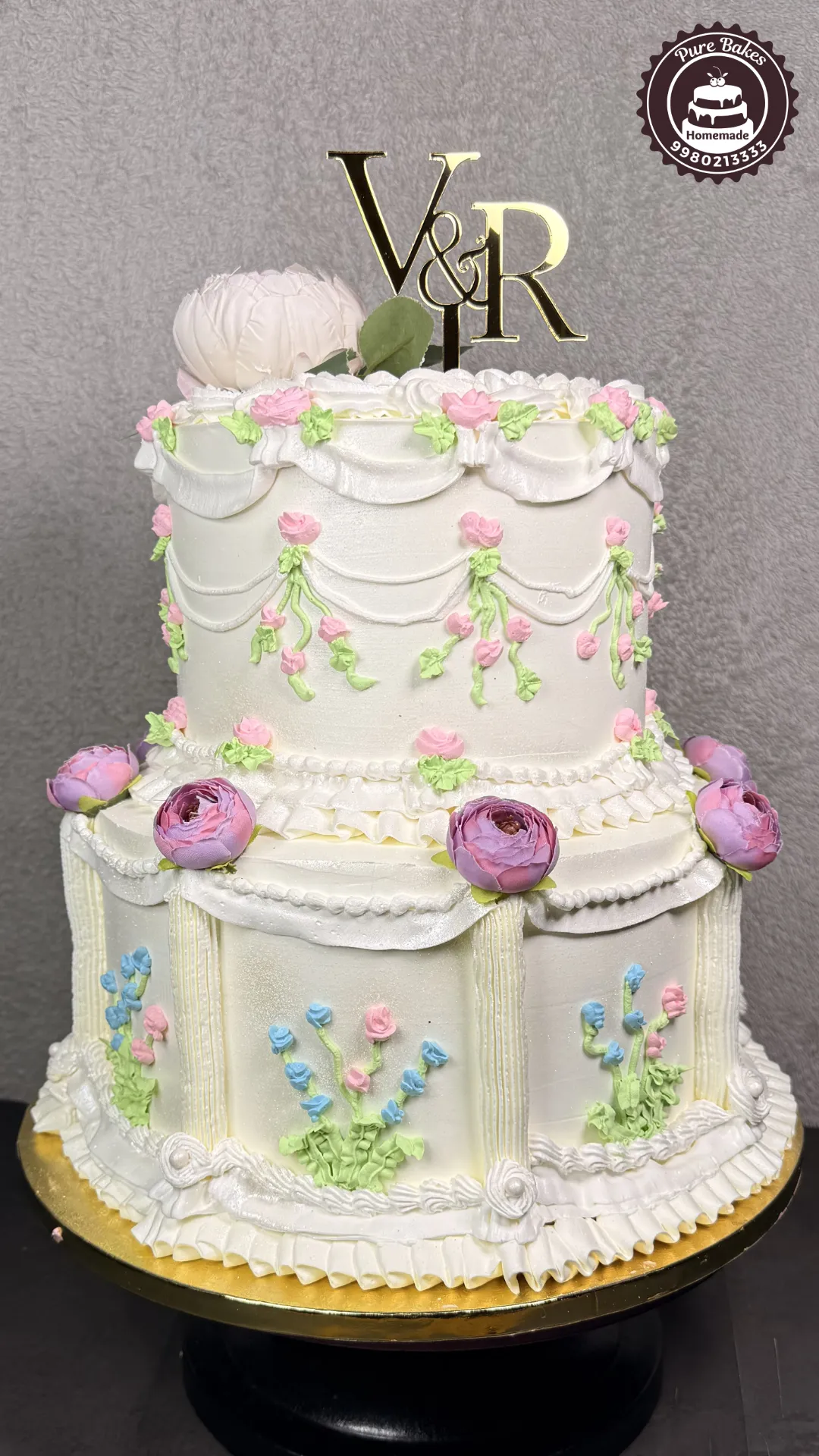 Two-tier floral wedding cake with buttercream garland decoration created by PureBakes
